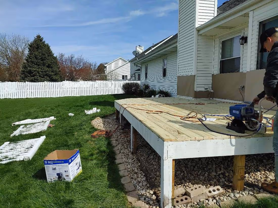 Partially built wooden deck attached to a house with construction tools and materials on and around it.